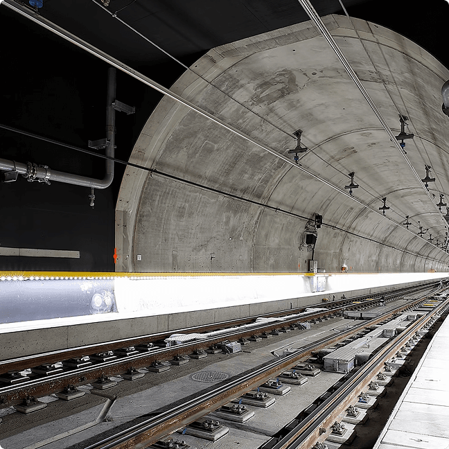 Underground train tunnel with dual railway tracks and overhead lighting.
